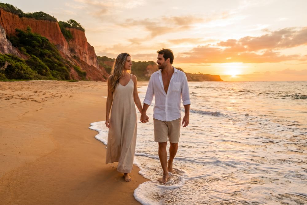 Casal em momento de descanso diante da paisagem de falésias e mar em Trancoso, Bahia