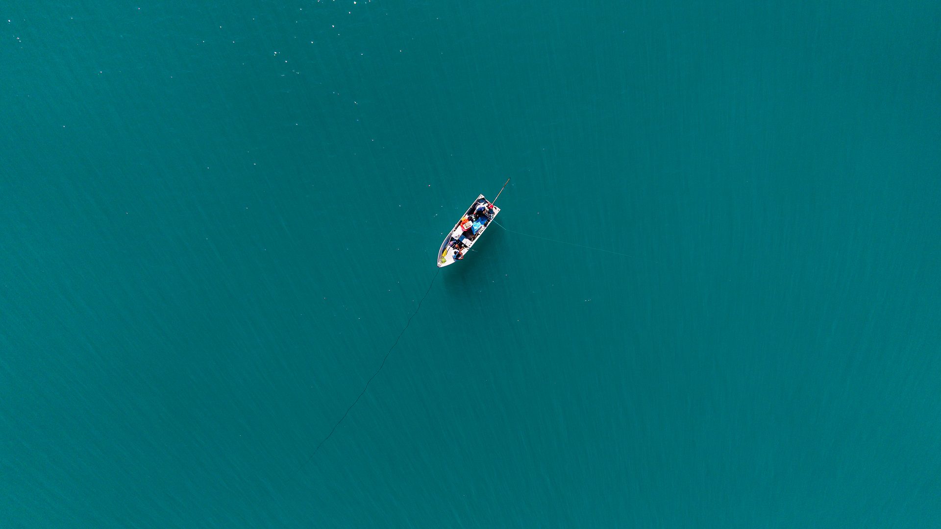 Barco solitário em mar turquesa diante de Taípe, Trancoso